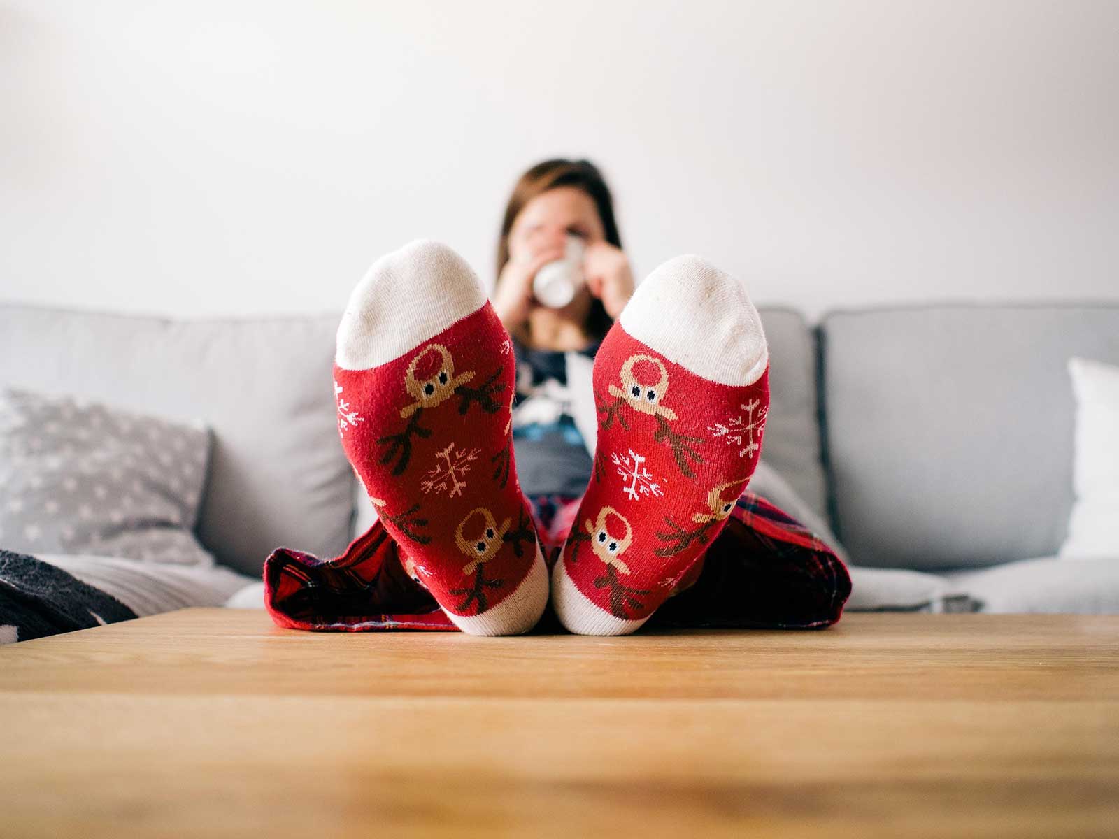 A woman wearing Christmas socks on the sofa