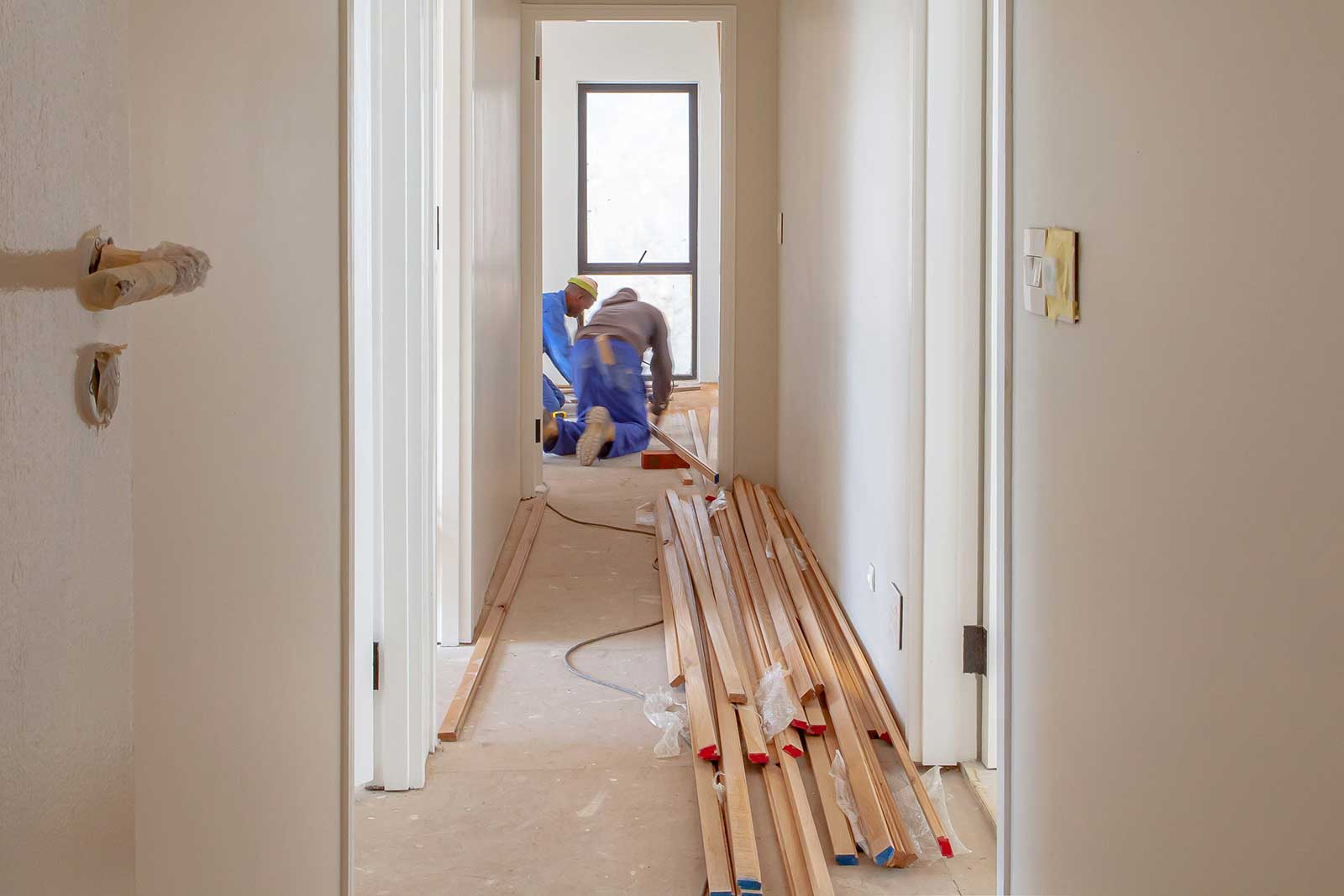 Messy central heating installation with engineers lifting floorboards for copper pipework.