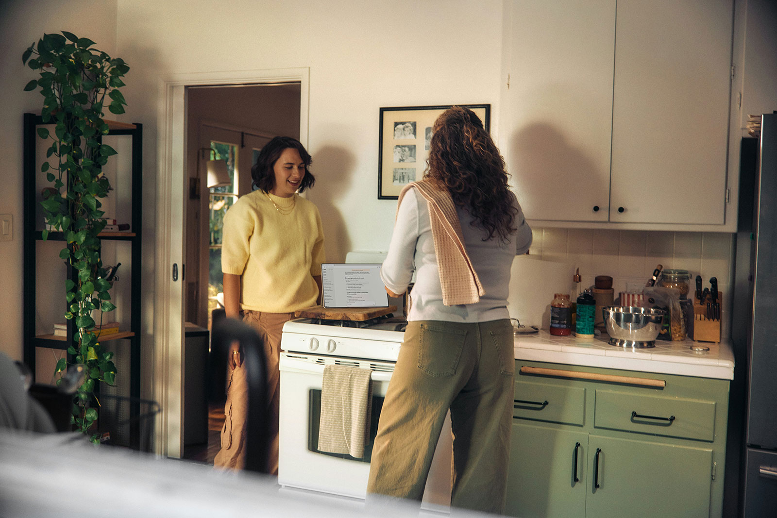 Two tenants standing in a modern green kitchen discussing home utility bills next to a domestic cooker.